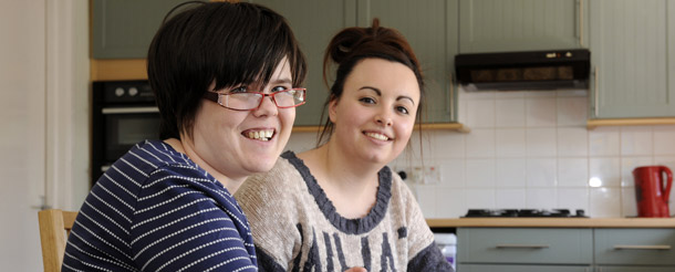 Young carer and girl smiling in kitchen