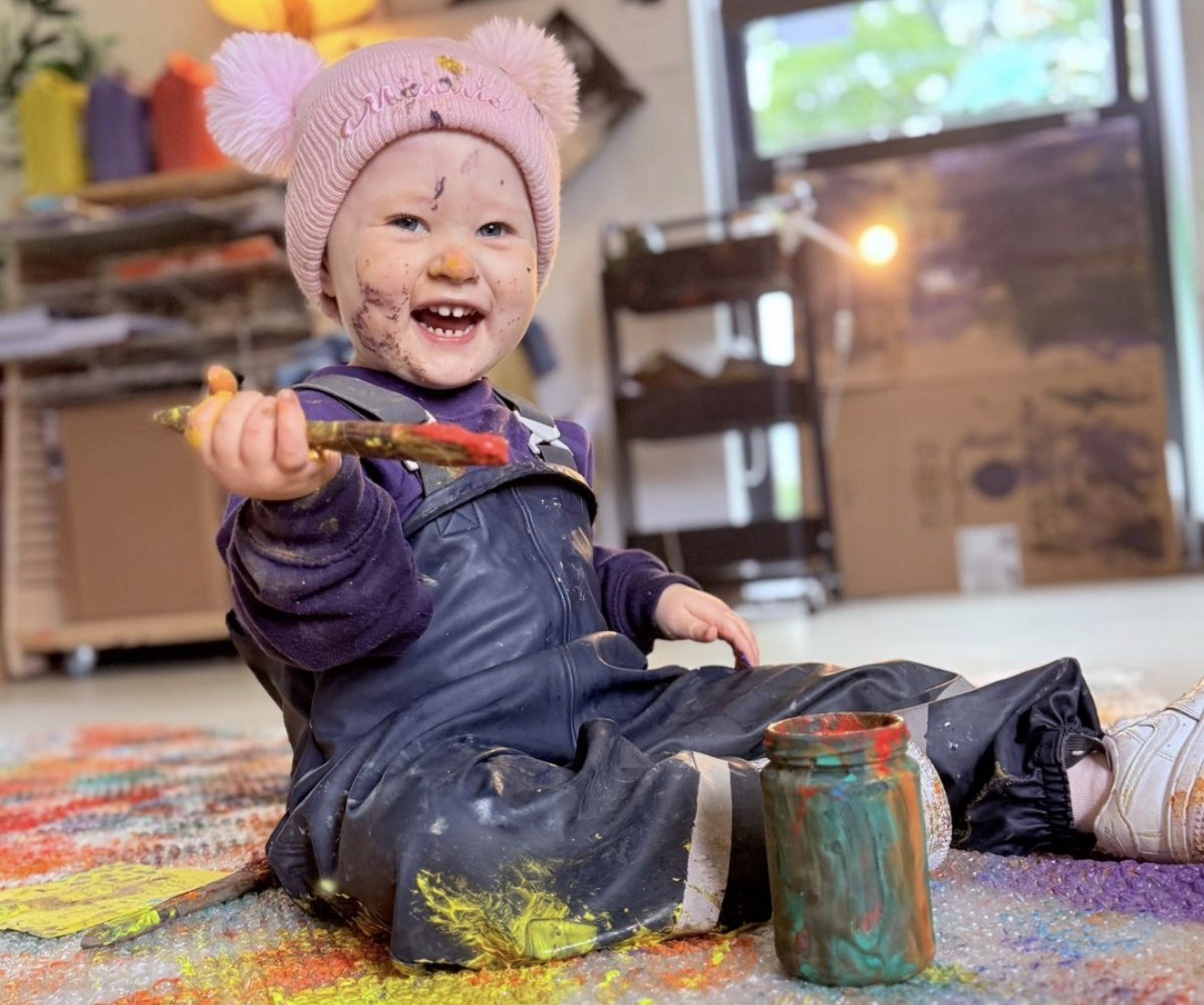Smiling child playing with paintbrush.