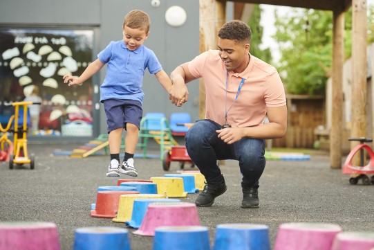 nursery worker with child in playground