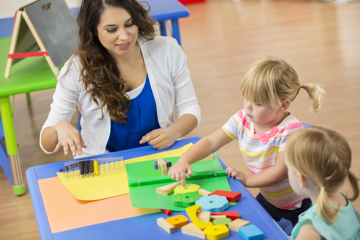 Daycare teacher works with students on learning exercise