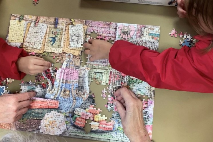 Pensioner and child playing with jigsaw